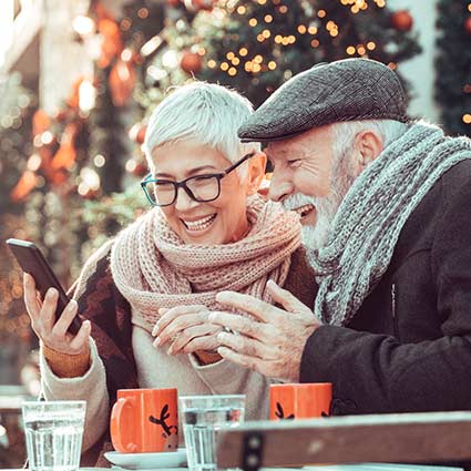 Retired couple smiling and looking at their phone.