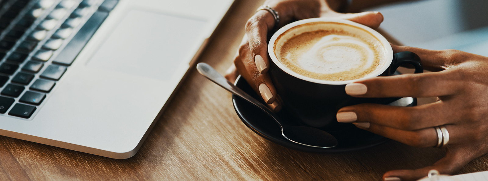 Coffee in hands in front of a laptop.