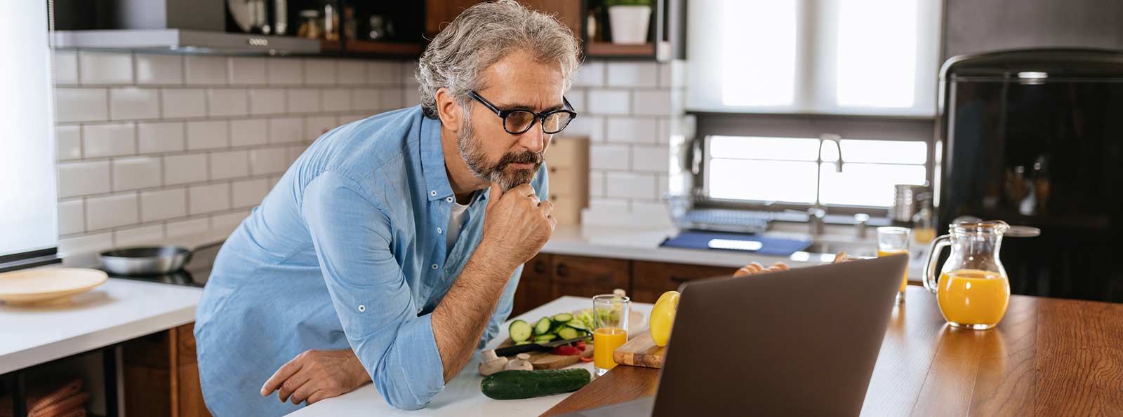 Man in the kitchen staring at his laptop.